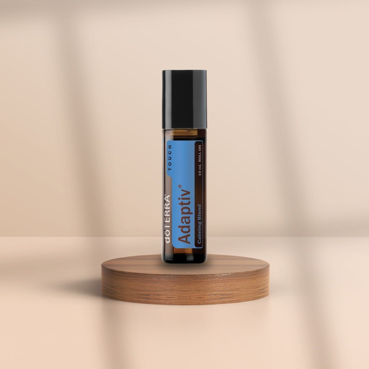 Braunglasflasche dōTERRA Adaptiv Touch 10 ml auf Holzpodest – ätherische Öl-Mischung im Roll-On für emotionale Balance, Fokus und innere Ruhe.
