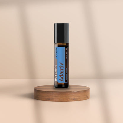 Braunglasflasche dōTERRA Adaptiv Touch 10 ml auf Holzpodest – ätherische Öl-Mischung im Roll-On für emotionale Balance, Fokus und innere Ruhe.