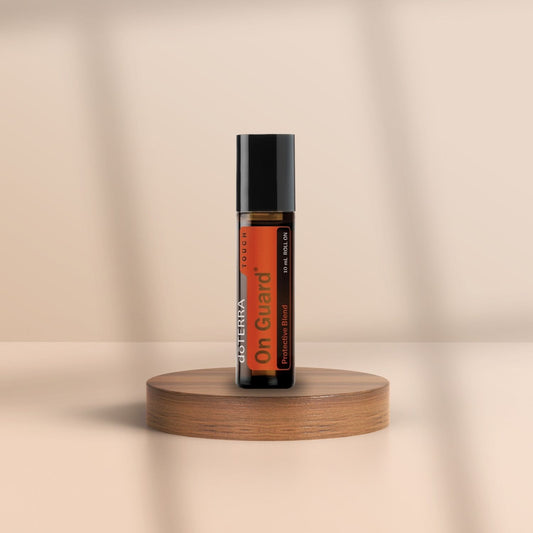 Braune Roll-On-Flasche von doTERRA On Guard auf Holzpodest, vor neutralem Hintergrund.