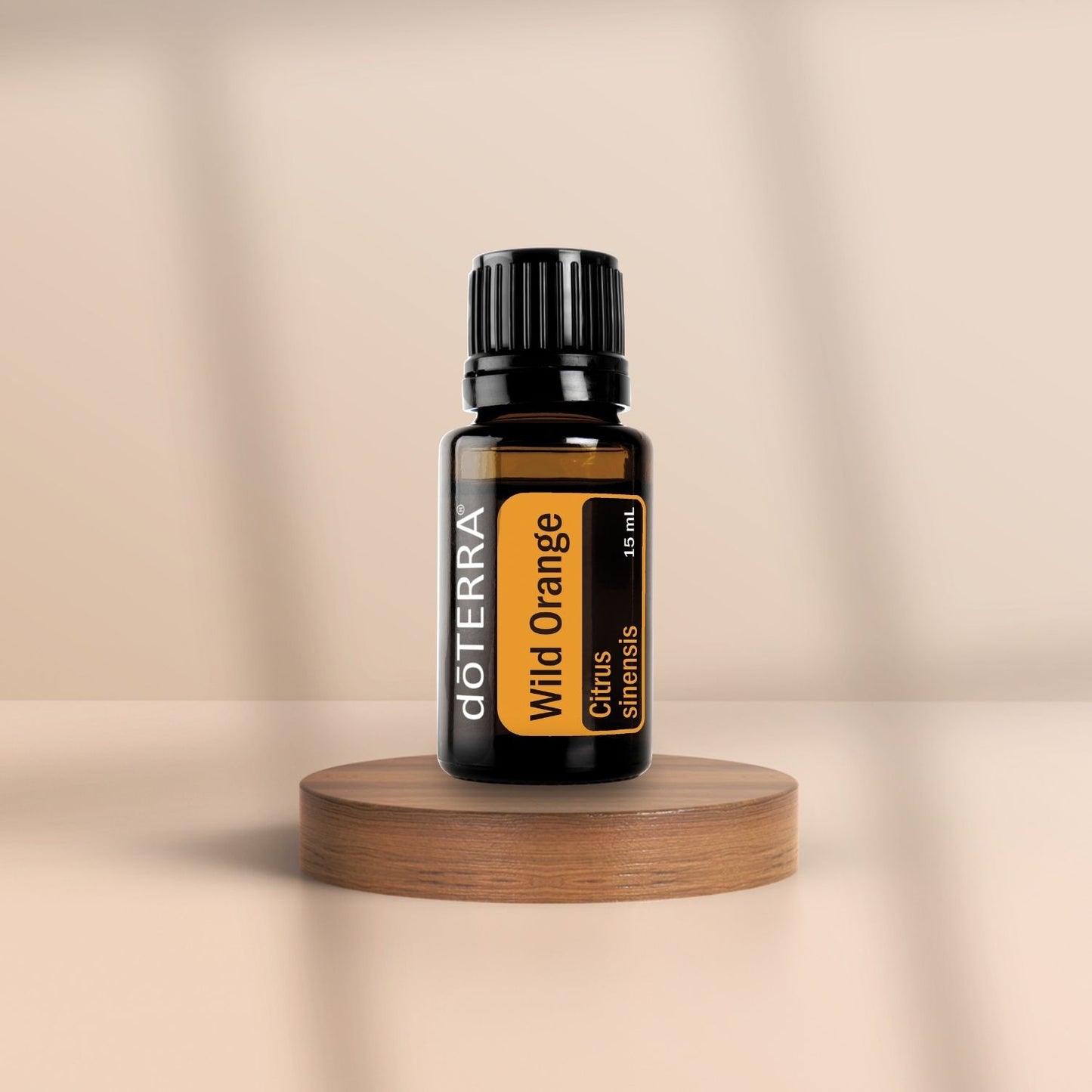 Braunes Glasfläschchen mit schwarzem Deckel – doTERRA Wild Orange (15 ml), platziert auf einem runden Holzpodest vor beigem Hintergrund.