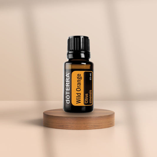 Braunes Glasfläschchen mit schwarzem Deckel – doTERRA Wild Orange (15 ml), platziert auf einem runden Holzpodest vor beigem Hintergrund.