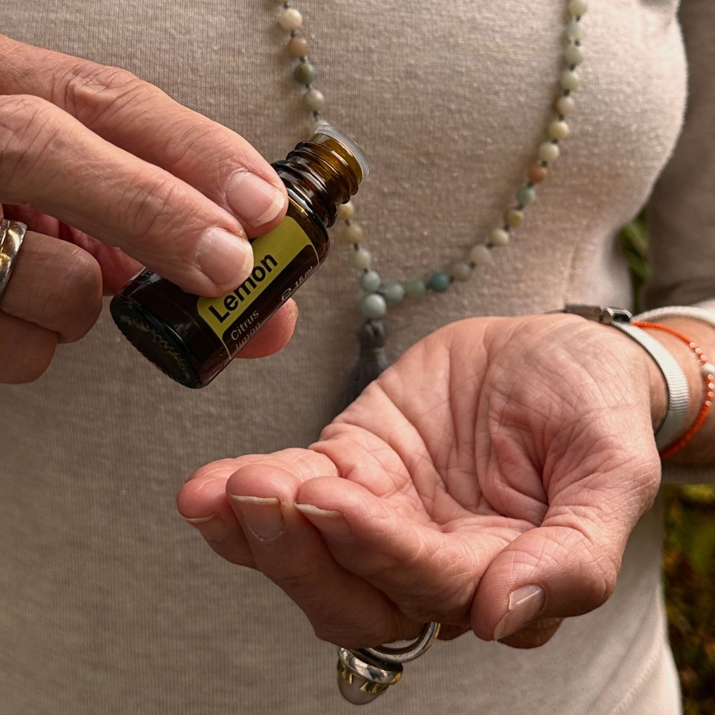 Eine Person tropft ätherisches Zitronenöl von dōTERRA in die Hand – Symbol für natürliche Frische, Energie und Achtsamkeit im Alltag